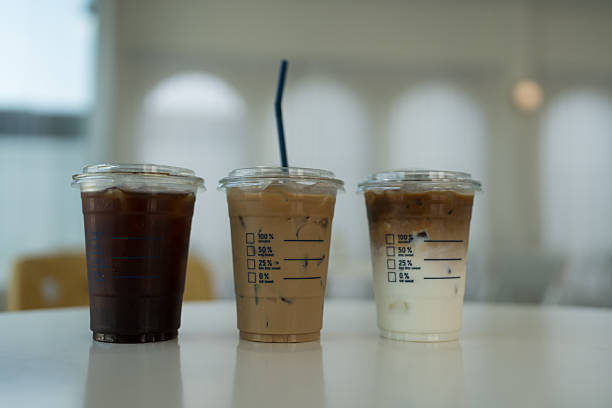Three take away iced coffee drinks sitting on a cafe table,  iced americano, iced mocha and iced latte.