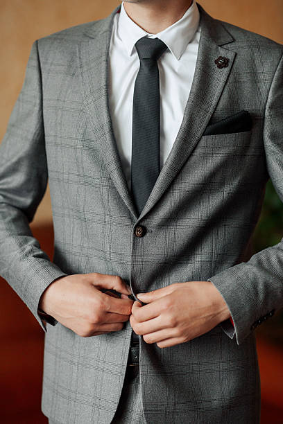 istock A man in a gray suit and white shirt is adjusting his tie 2210338780