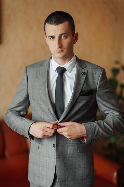 istock A man in a gray suit and white shirt is adjusting his tie 2210338791