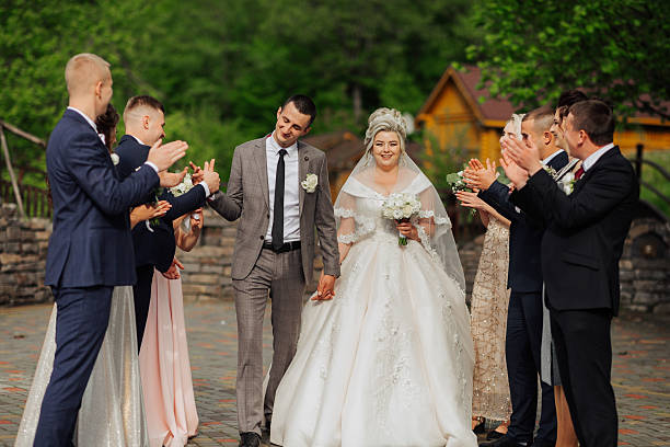 istock A bride and groom are walking down a path with their wedding party behind them 2210338835