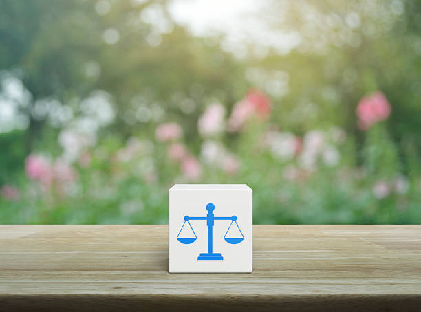Law flat icon on white block cube on wooden table over blur pink flower and tree in garden, Business legal service concept