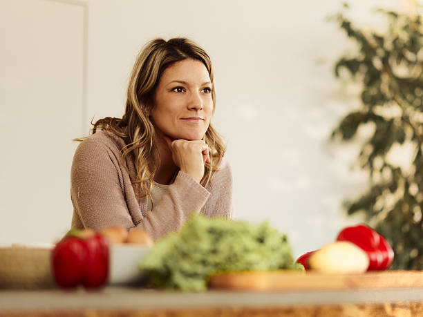 istock Smiling woman day dreaming in the kitchen. 2210340847