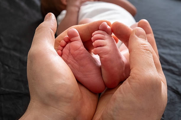 istock Tender Moment: Holding Newborn Baby Feet 2210341740