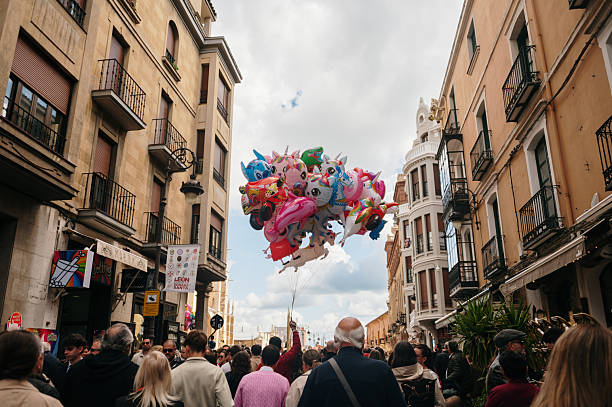 Leon, Spain - 13 April, 2025: A crowd of people and a person with many balloons for sale in a street of Leon, Spain