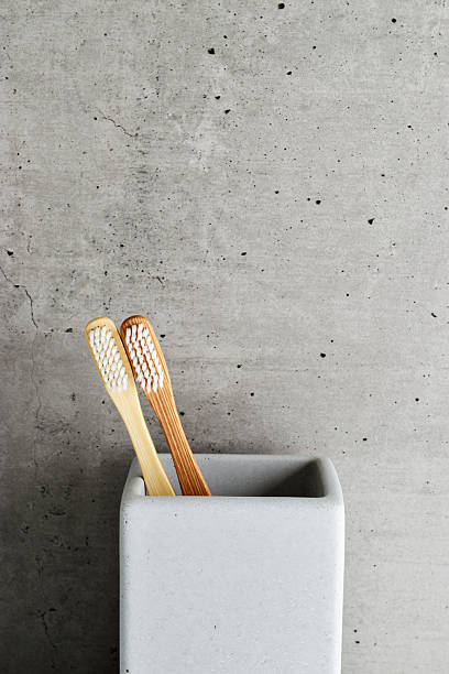 istock Eco-friendly wood toothbrushes with soft white bristles in modern grey concrete holder. Minimal bathroom design, sustainable hygiene concept, Neutral tones, zerowaste lifestyle, eco-conscious living 2210342975