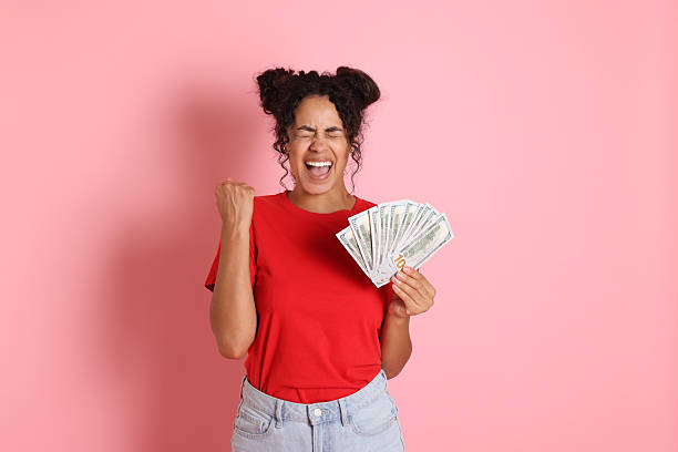istock Happy woman with dollar banknotes on pink background 2210346417