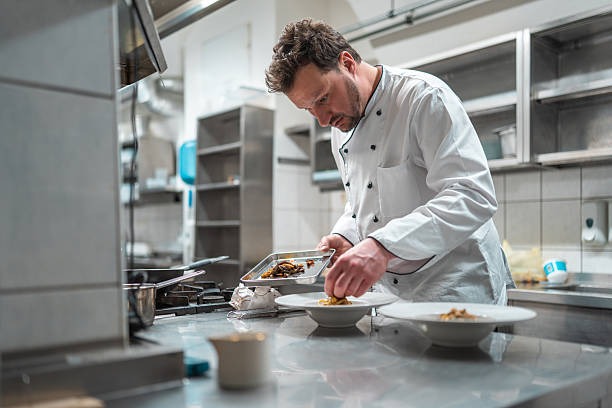 istock Professional Chef Carefully Plating Gourmet Dish In Modern Restaurant Kitchen 2210347691