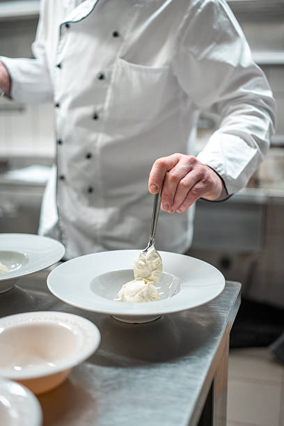 istock Professional Chef in White Double-Breasted Jacket Carefully Plating Gourmet Dessert 2210347696