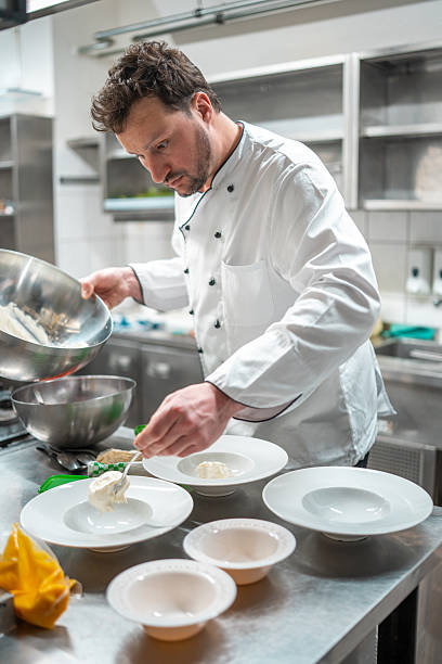 istock Male Chef in White Uniform Plating Dishes in Modern Professional Kitchen 2210347706