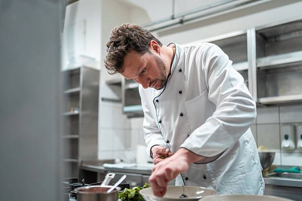 istock Professional Chef Plating Gourmet Dish in Modern Stainless Steel Kitchen 2210347721