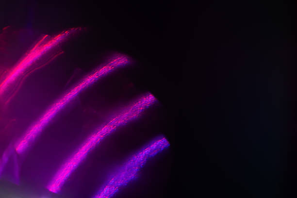 Blur neon light. Lens flare overlay. Bokeh fluorescent flash gleam. Defocused blue purple color flecks on dark black abstract background.