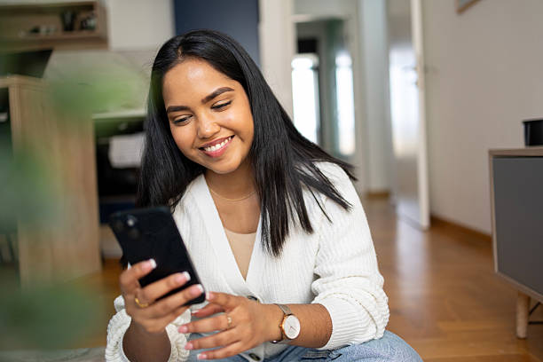istock Smiling Indian woman using mobile phone at home 2210356901