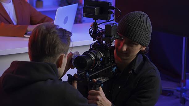 istock Backstage video production recording. The assistant helps the videographer set up the camera. 2210359002