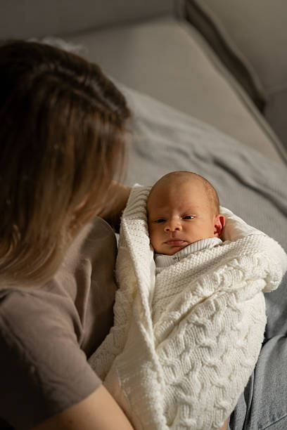 istock Mom gently holds her wrapped baby in a cozy indoor setting while sharing a quiet moment together during the early morning hours 2210359364