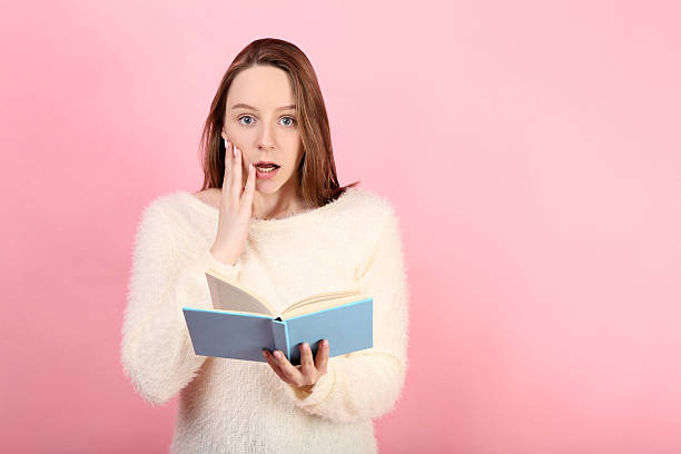 Young girl with book on pink background