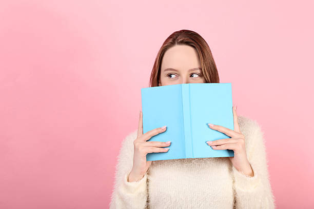istock Young girl with book on pink background 2210363201