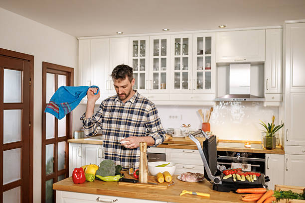 Portrait of happy man standing by kitchen island and cutting vegetables while preparing healthy meal at home