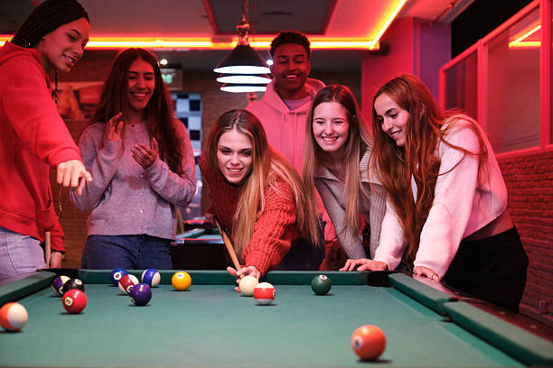 Group of friends enjoying a game of pool in a trendy, neon-lit bar