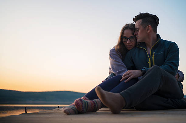 Couple on the pier at lake, summer sunset