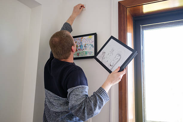 istock Father hanging daughter's drawings on the wall at home 2210365026