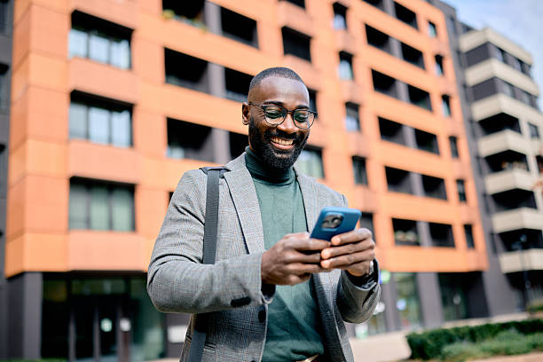 istock Smiling businessman using smartphone in front of modern building 2210367015