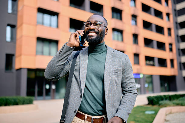 istock Smiling businessman talking on phone walking near office building 2210367018