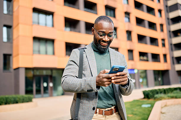 istock Smiling businessman using smartphone in front of modern building 2210367019