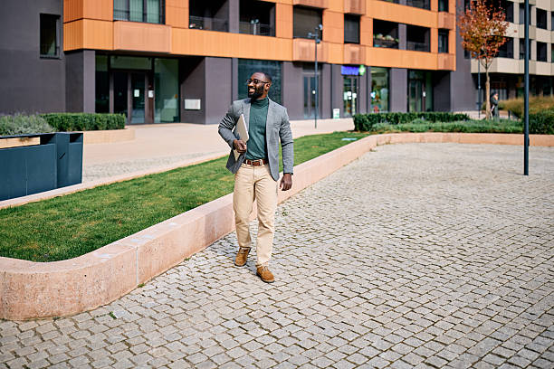istock Businessman walking outdoors holding a laptop and smiling 2210367023
