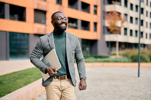 istock Smiling businessman walking outside carrying laptop 2210367061