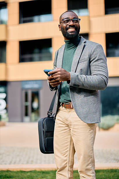 istock Smiling businessman using smartphone and carrying briefcase outdoors 2210367062