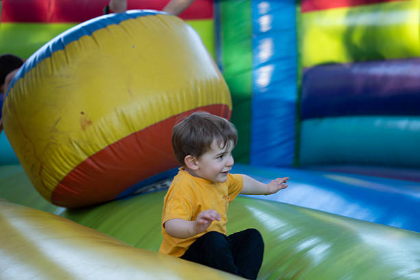 Young boy having fun jumping and playing on a colorful inflatable bouncy castle in a playground