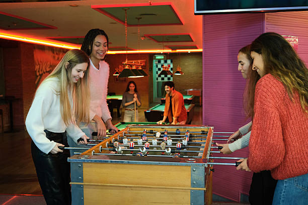 istock Four friends playing foosball in a games room 2210367683