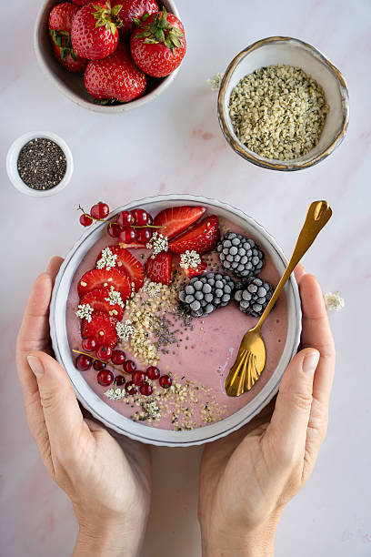 istock A healthy smoothie bowl with fruit and seeds and hands vertical 2210368818