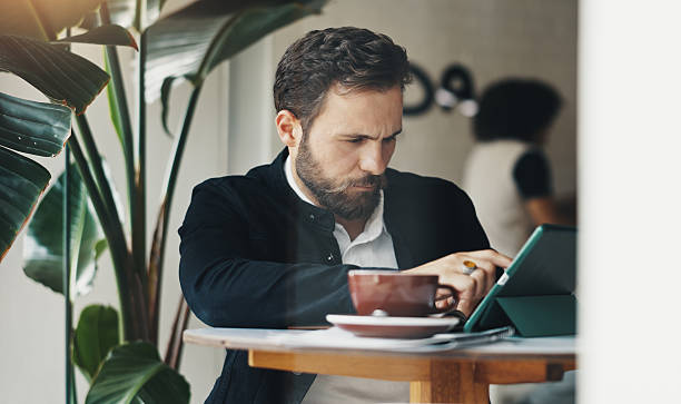 istock Remote work, man and typing on tablet in cafe for email communication, online report and freelancing. Entrepreneur, editing and tech in coffee shop for business, startup proposal and web research 2210369320