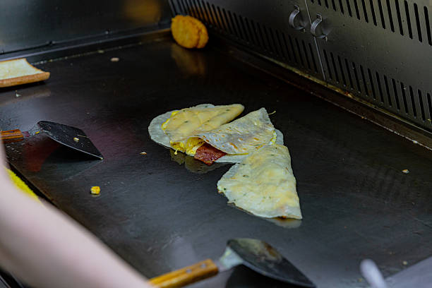 istock Taiwanese breakfast wraps egg, ham hash brown being grilled folded hot griddle, mid-cook at local morning food stall 2210369685