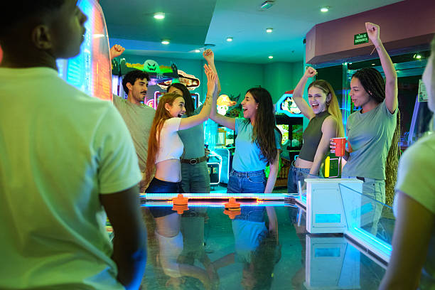 istock Excited young adults giving high five while playing air hockey in an arcade 2210370041