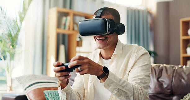 istock Man, vr goggles and video game on sofa, controller and happy in home for challenge in 3D metaverse. Person, augmented reality and glasses with futuristic ux, play and smile with click at apartment 2210371118