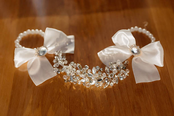 A pair of white bows are displayed on a wooden table. The bows are made of silver and are adorned with crystals. Concept of elegance and sophistication