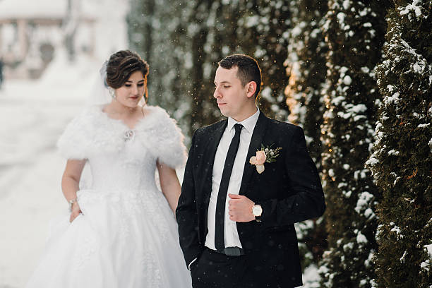 istock A bride and groom are walking down a snowy path 2210371367