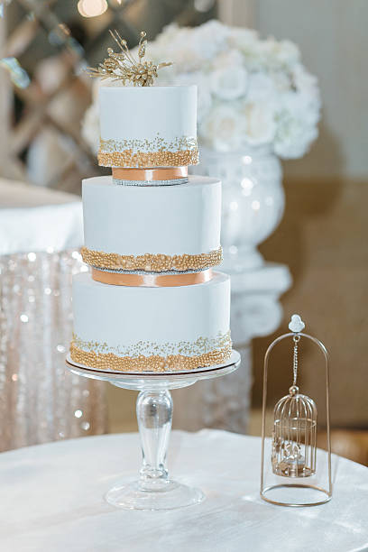 istock A three tier wedding cake with gold trim sits on a glass stand 2210371402