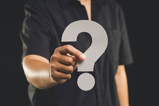 istock Hand holding a white question mark symbol against a black background. 2210371527