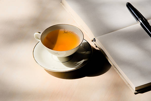 istock Tea in porcelain cup and journal on wooden table 2210371689