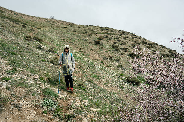 Young women walking on a rocky hillside with blooming trees in the background
