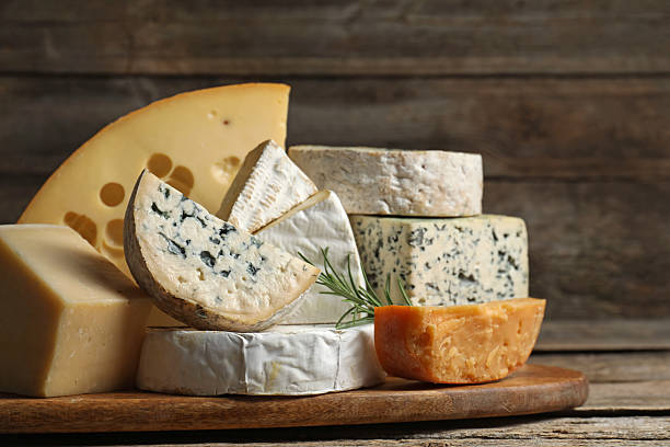 istock Different types of cheese and rosemary on wooden table, closeup 2210374385