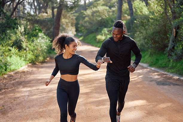 Fist bump, running and friends in nature for exercise, marathon training and cardio workout. Sports, happy and man and woman with support, motivation and goals for fitness, endurance or challenge