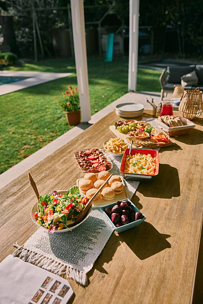 Large silver bowl filled with fresh strawberries, pears, and apples surrounded by flowers during an outdoor event.