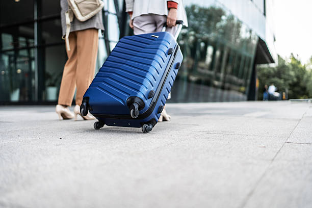 istock Businesswomen walking with rolling suitcase at airport 2210375512