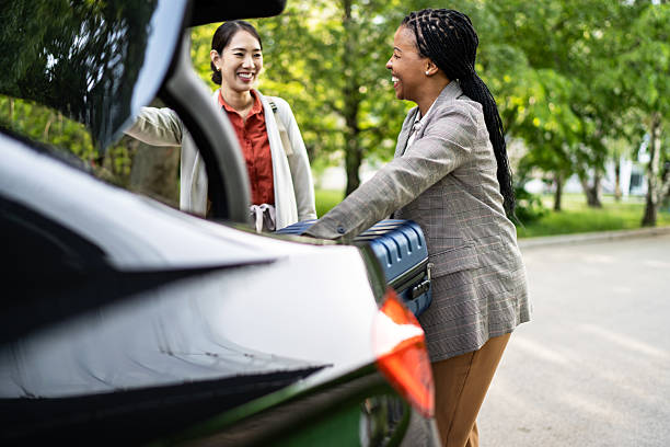 istock Two businesswomen loading luggage into car trunk before road trip 2210375869