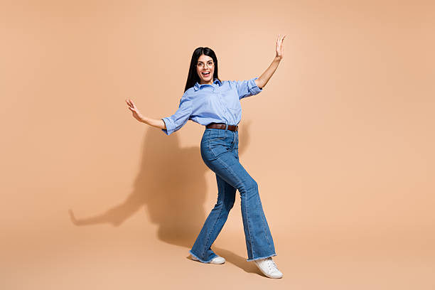 istock Charming young woman in casual attire posing with dynamic gestures against beige background, showcasing positive energy and trendy style 2210376558