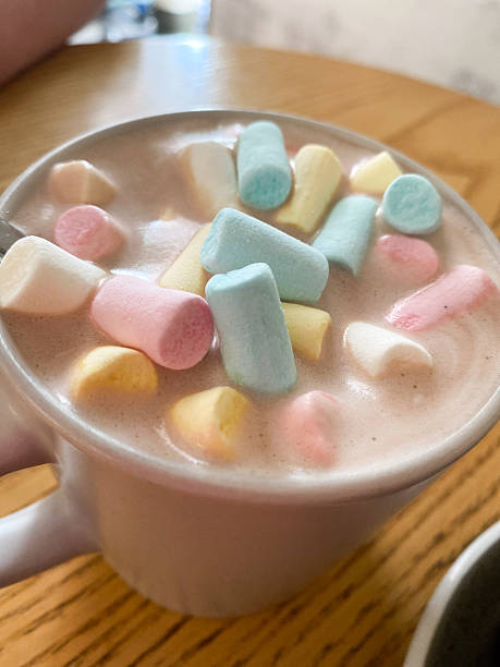 Homemade marshmallows around grey cup with cocoa or hot chocolate over top. pink marshmallow like rose close-up. Present for woman on valentines day. Sweets from natural products without GMOs.